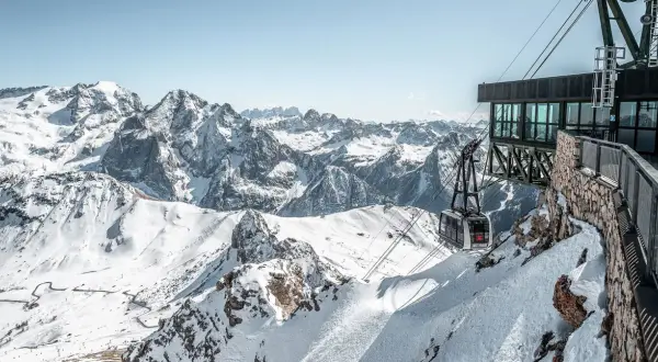 Panoramica mozzafiato dal belvedere di Canazei: una funivia scende tra le cime innevate delle Dolomiti.