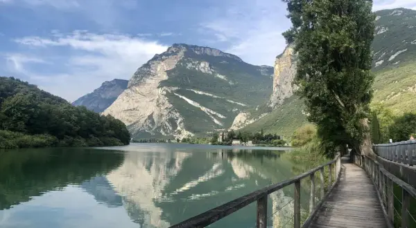 Passeggiata sul lungolago di Toblino, con montagne maestose che si specchiano nelle acque calme.
