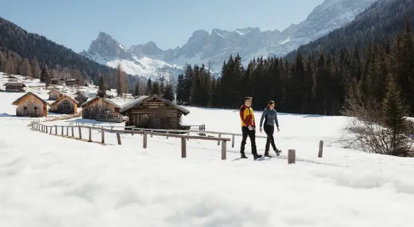Coppia in escursioni invernali Trentino, tra baite innevate e montagne maestose.