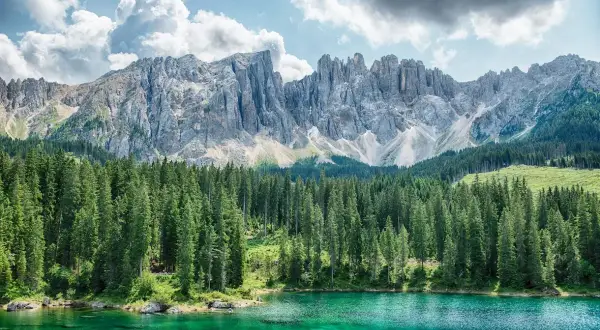 Lago di Carezza, un gioiello del Val di Fiemme cosa vedere. Montagne maestose, boschi di abeti e acque cristalline.