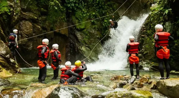 Avventura di canyoning in Trentino: un gruppo si prepara a scendere una cascata, immersi nella natura selvaggia.