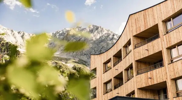 Il Falkensteiner Hotel Antholz si fonde con le maestose montagne. Architettura moderna in legno e natura incontaminata.