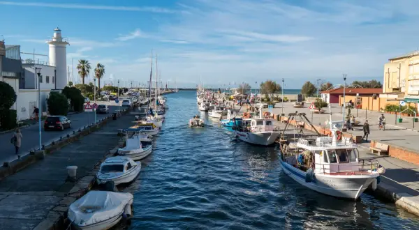 Porto di Viareggio con barche ormeggiate e un faro bianco. Ideale per scoprire cosa fare a Viareggio, tra passeggiate sul molo e gite in barca.