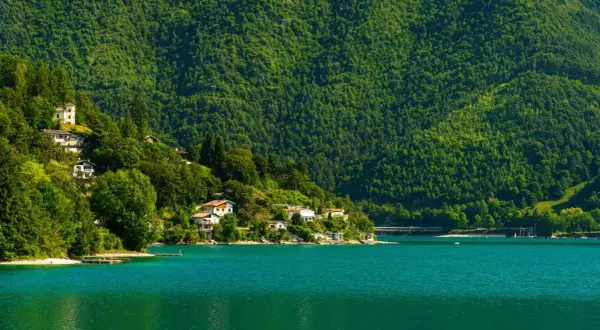 Case aggrappate alla collina verdeggiante che si specchia nel lago di Ledro, un'oasi di pace.