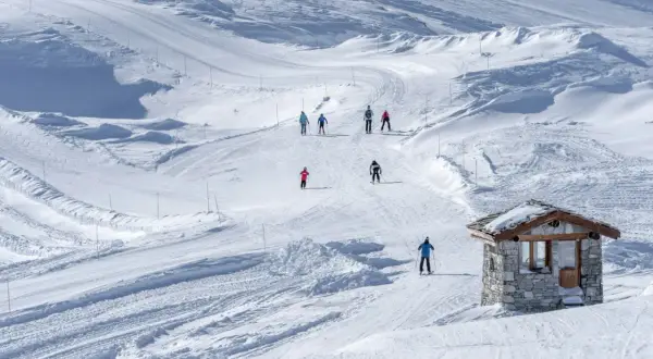 Sciare su piste battute, un piccolo rifugio in pietra e sciatori che godono della loro settimana bianca.
