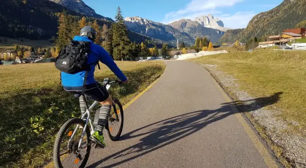 Ciclista su una strada panoramica tra le montagne del Trentino, godendosi le ciclabili.
