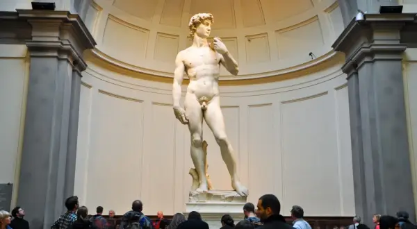 Il David di Michelangelo nella Galleria dell'Accademia di Firenze, ammirato da visitatori.