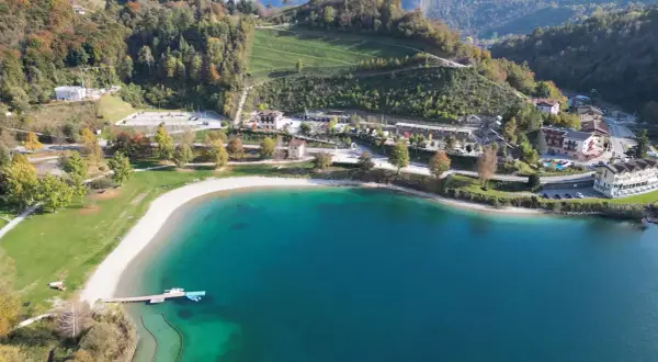 Vista aerea del lago di Ledro con spiaggia e campeggio. Un luogo ideale per il best Ledro camping, con acque cristalline e montagne verdi.