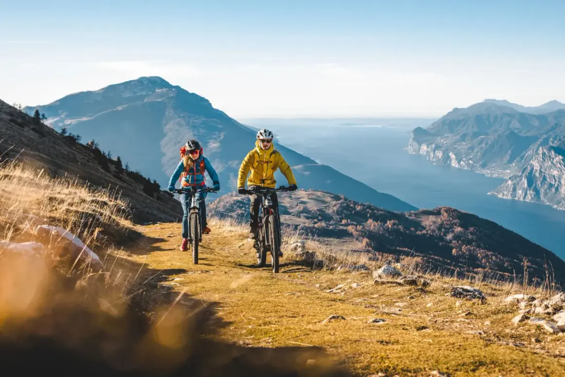 Coppia in mountain bike sui percorsi mtb Trentino, con vista mozzafiato sul lago e le montagne.