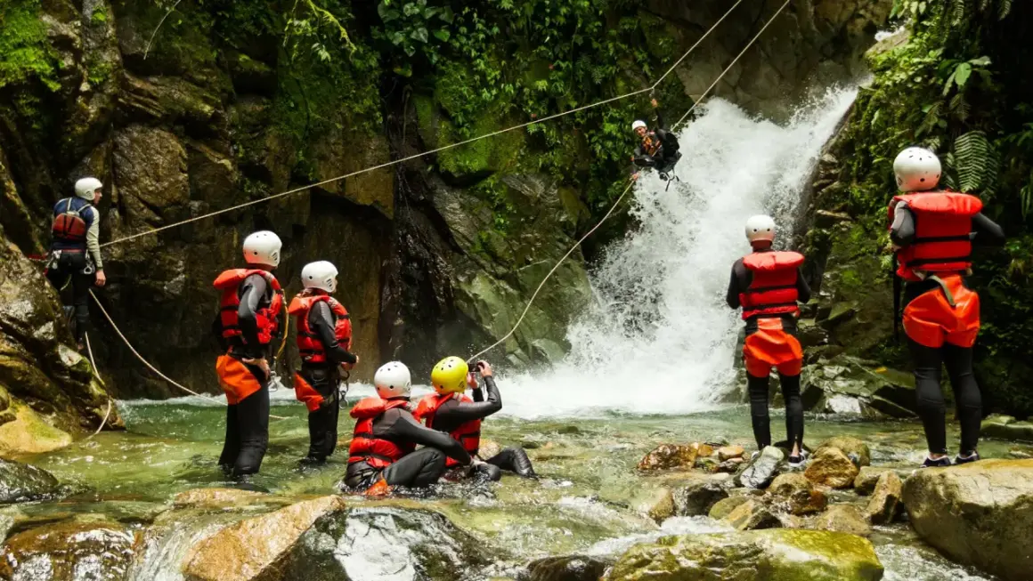 Avventura di canyoning in Trentino: un gruppo si prepara a scendere una cascata, immersi nella natura selvaggia.