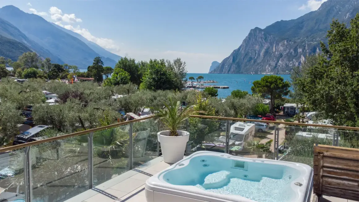 Vista da un idromassaggio su un camping Maroadi con lago e montagne.