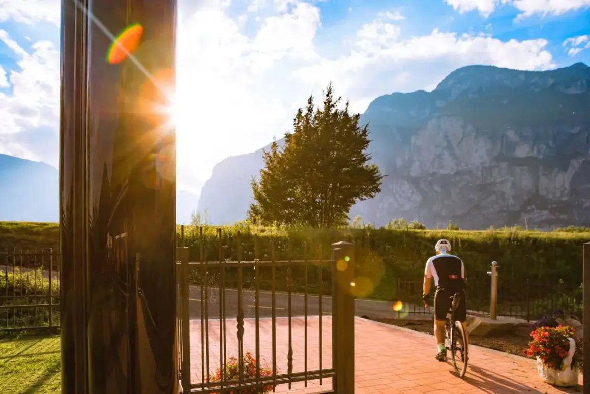 Ciclista in sella alla bici, con montagne sullo sfondo. Un raggio di sole illumina la scena vicino al bicigrill Faedo.