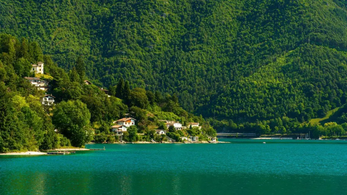 Case aggrappate alla collina verdeggiante che si specchia nel lago di Ledro, un'oasi di pace.