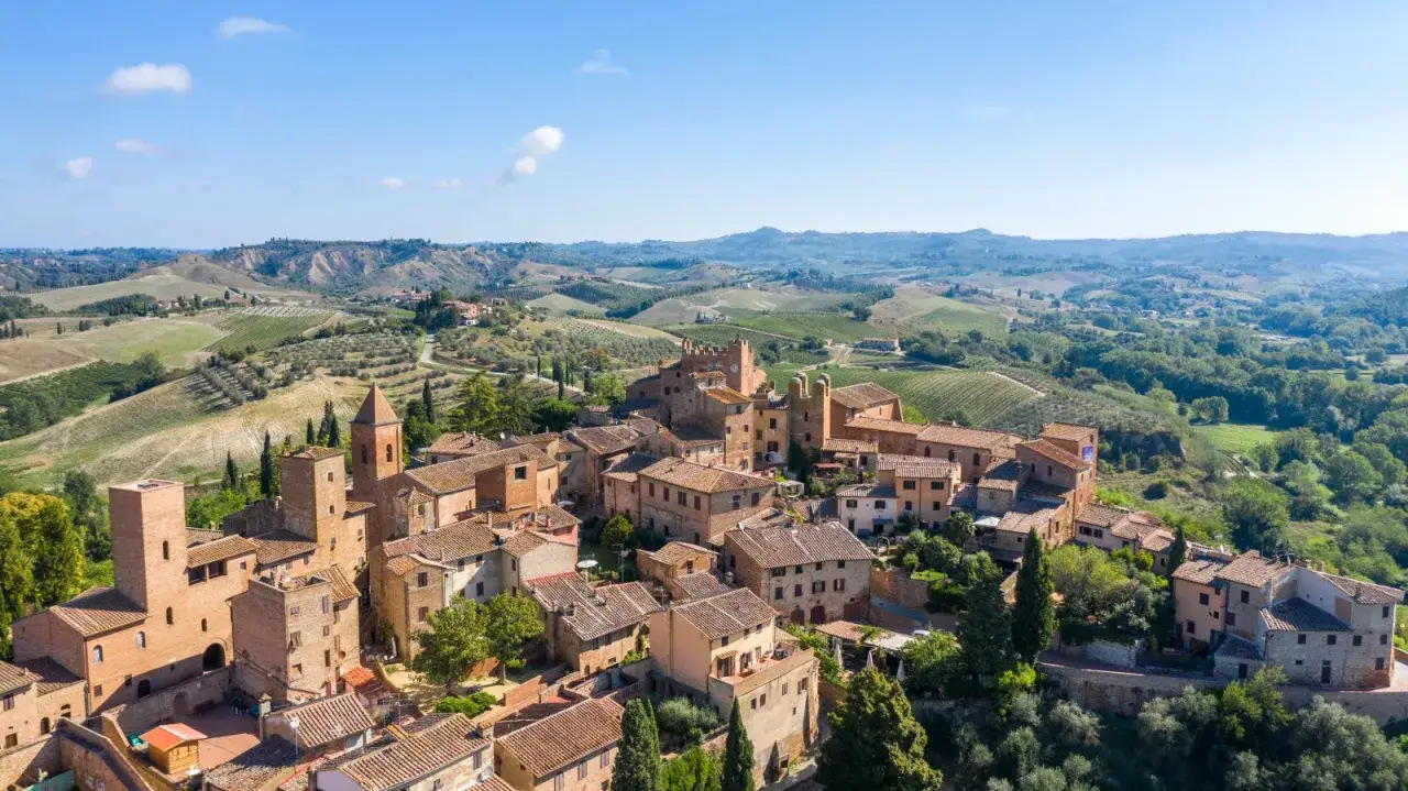 Panoramica aerea di Certaldo Alto, borgo medievale toscano con torri e case in pietra, immerso tra colline verdi e vigneti.