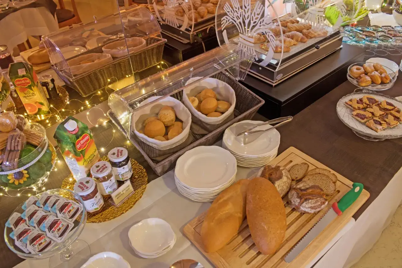 Buffet colazione con pane, dolci e succhi. Un'etichetta indica 