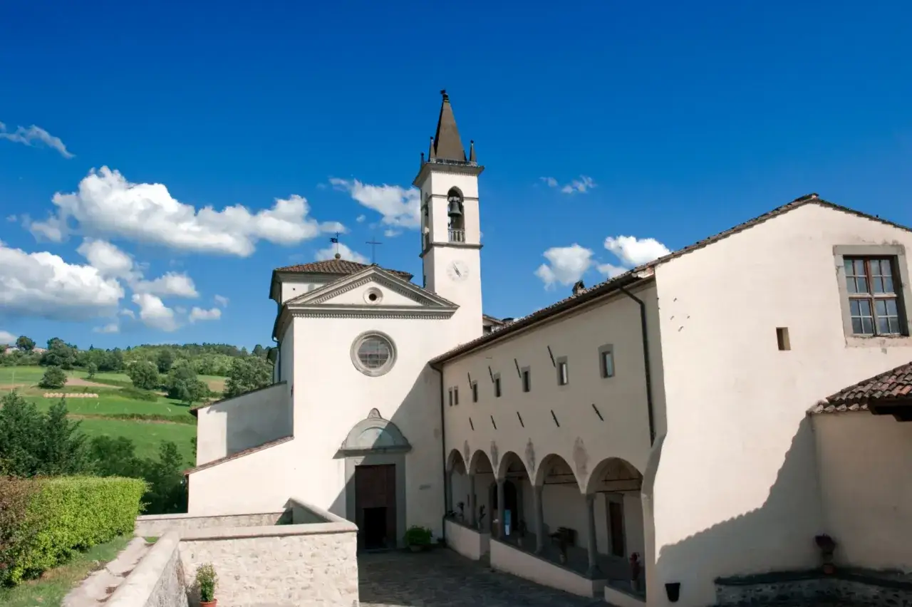 Un campanile svetta su un complesso religioso bianco, tra colline verdi. Un luogo da scoprire: Bibbiena cosa vedere.