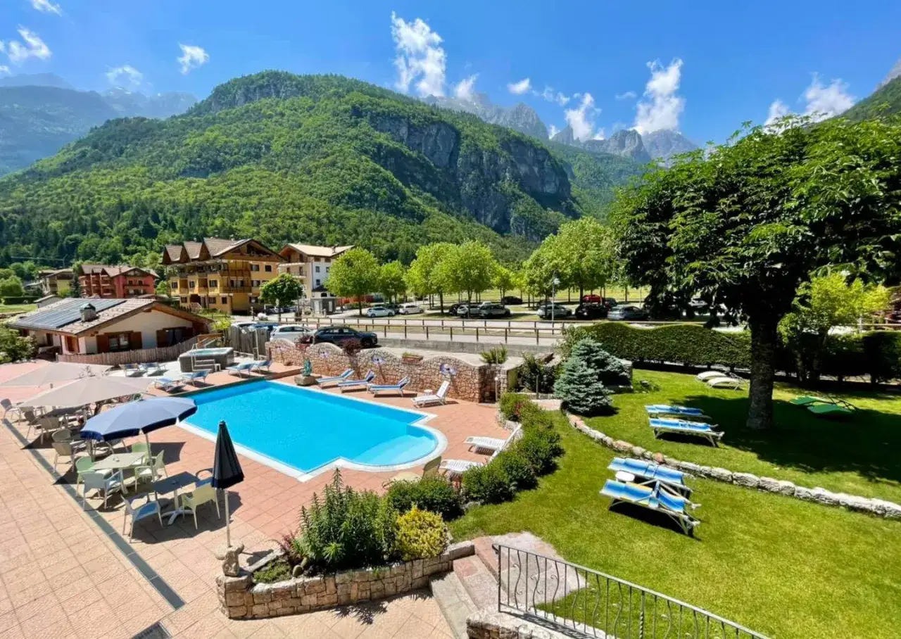 Piscina e prato curato con vista sulle montagne, un angolo di relax al Lago Park Hotel Molveno.