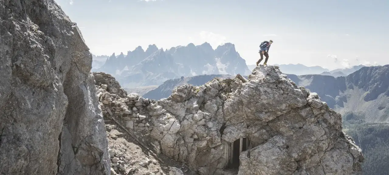 Escursionista su un crinale roccioso, con montagne nebbiose all'orizzonte. Un sentiero della pace tra le vette.