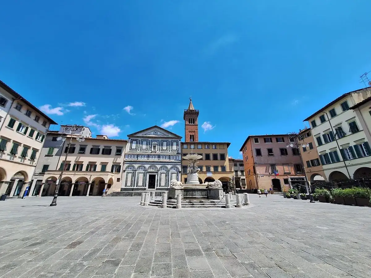 Piazza del Duomo a Empoli citt&agrave;, con la fontana dei leoni e la chiesa di Santa Maria Assunta sotto un cielo azzurro.