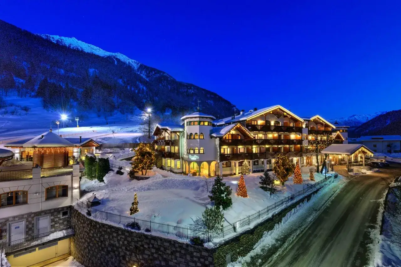 Kristiania Pure Nature Hotel & Spa, un incantevole hotel alpino immerso nella neve, illuminato da luci natalizie.