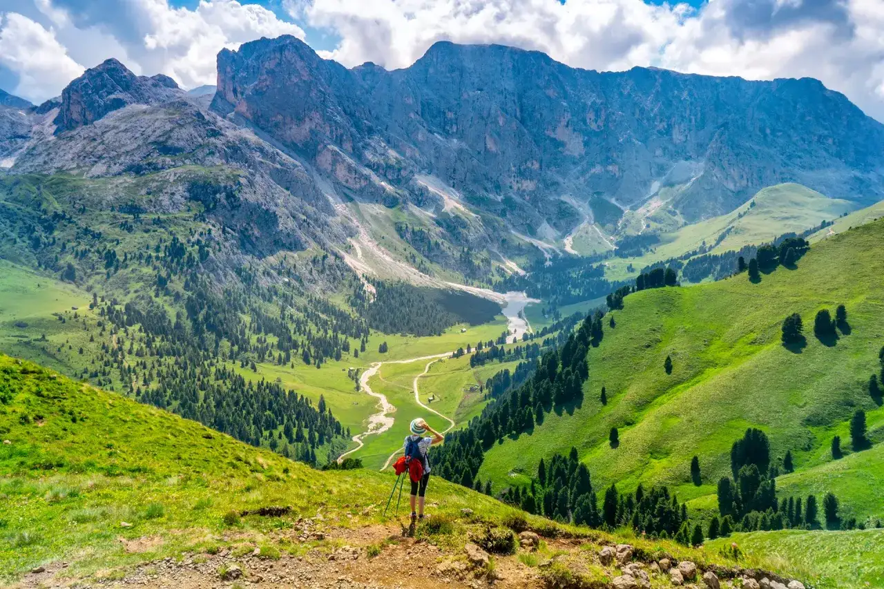 Escursionista ammira il panorama mozzafiato dal passo Duron, con valli verdi e montagne imponenti.