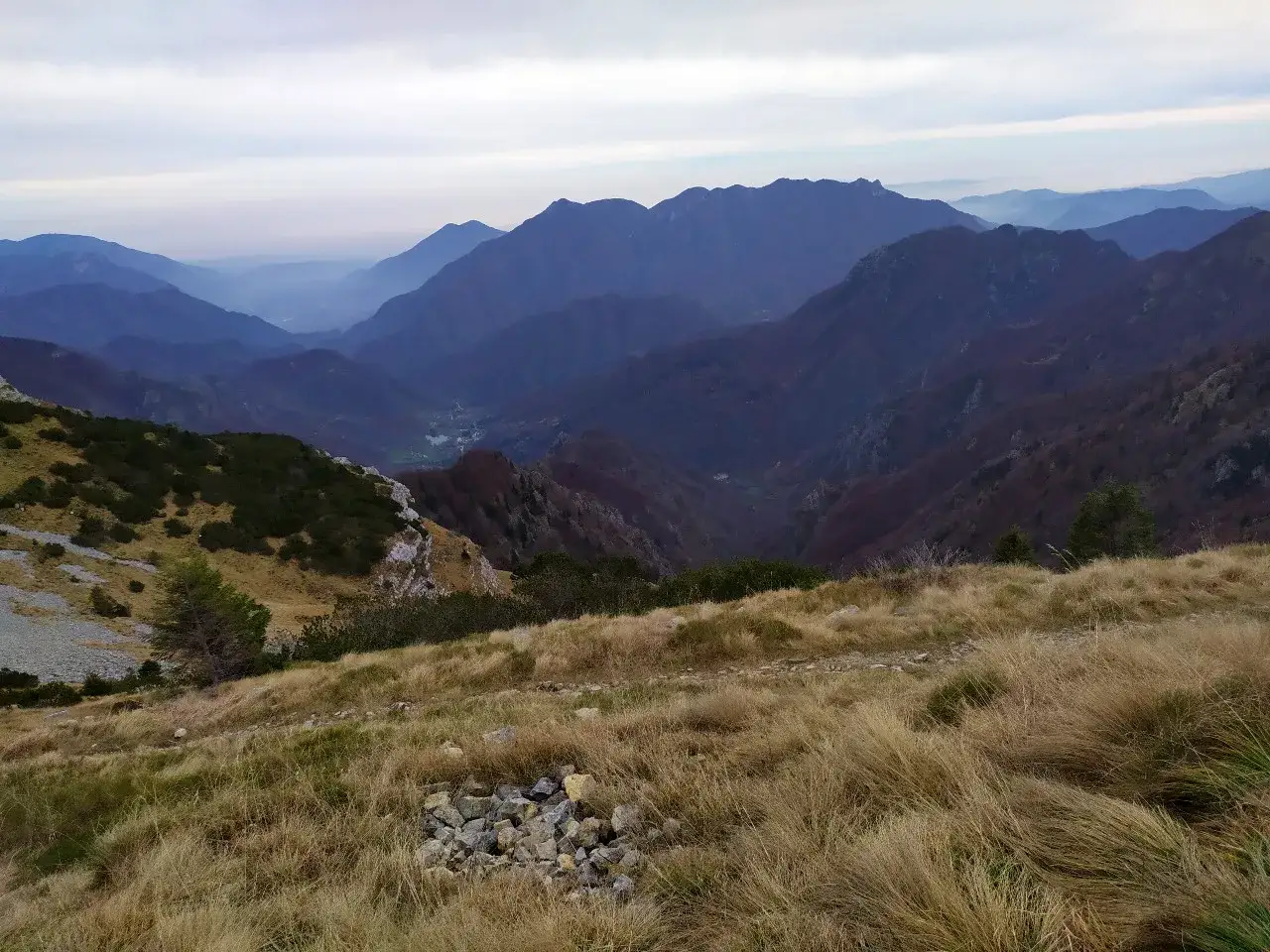 Panoramica mozzafiato del monte Maggio, con valli nebbiose e pendii coperti di erba secca e arbusti.