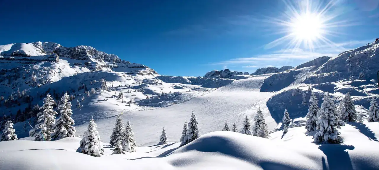 Sole splendente su Madonna di Campiglio, montagne innevate e piste da sci perfette. Alberi coperti di neve creano un paesaggio da fiaba.