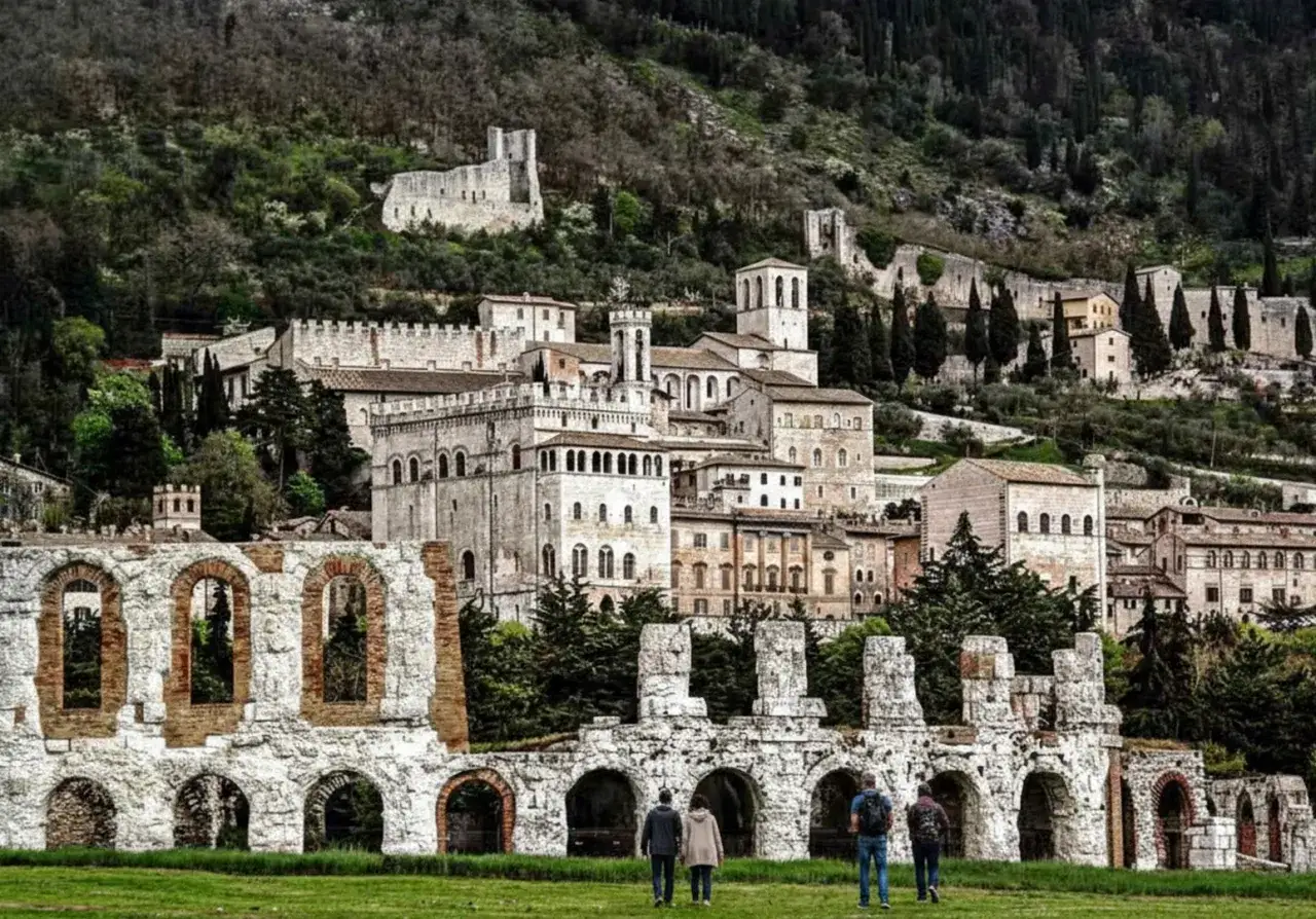 Antiche rovine romane a Gubbio, con il borgo medievale che si arrampica sulla collina. Un viaggio da Perugia a Gubbio tra storia e paesaggi umbri.