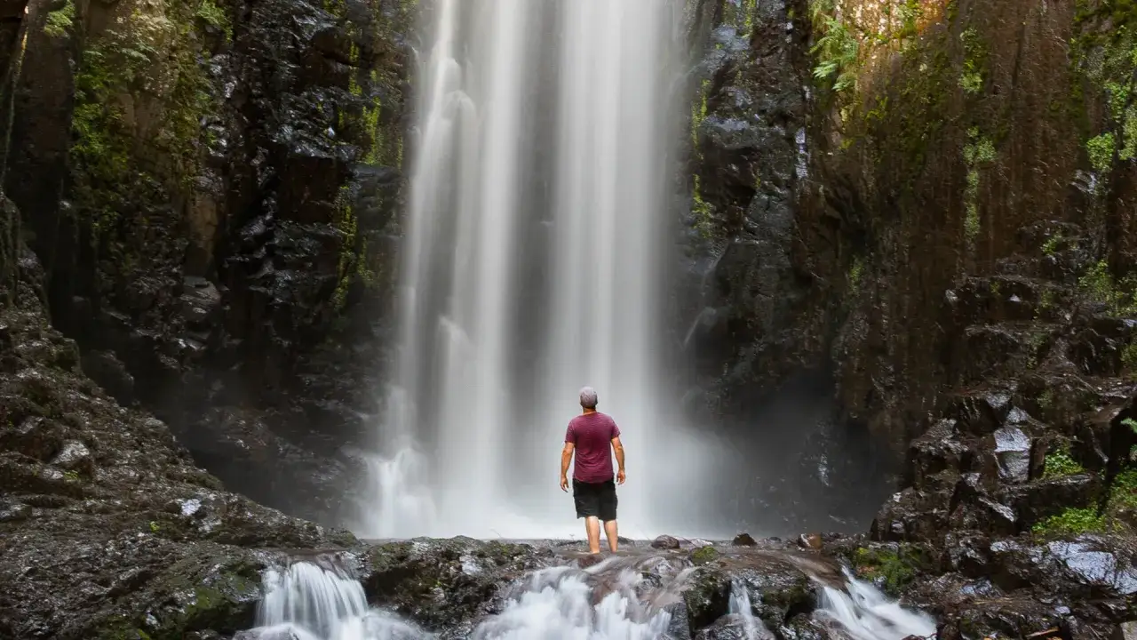 Un uomo in piedi di fronte alla cascata del lupo, immerso nella natura selvaggia.