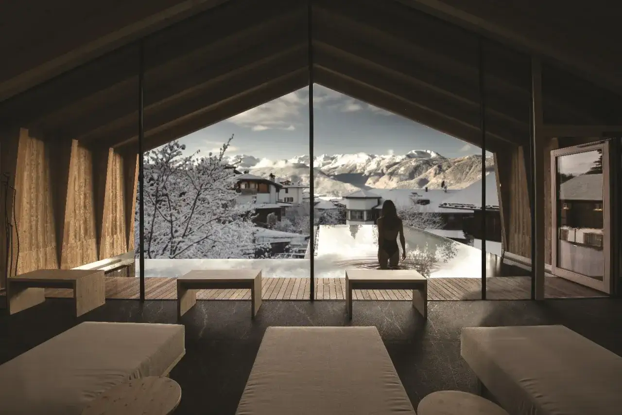 Interno di un resort di lusso con piscina a sfioro e vista sulle montagne innevate. Un'oasi di pace nel pineta nature resort.