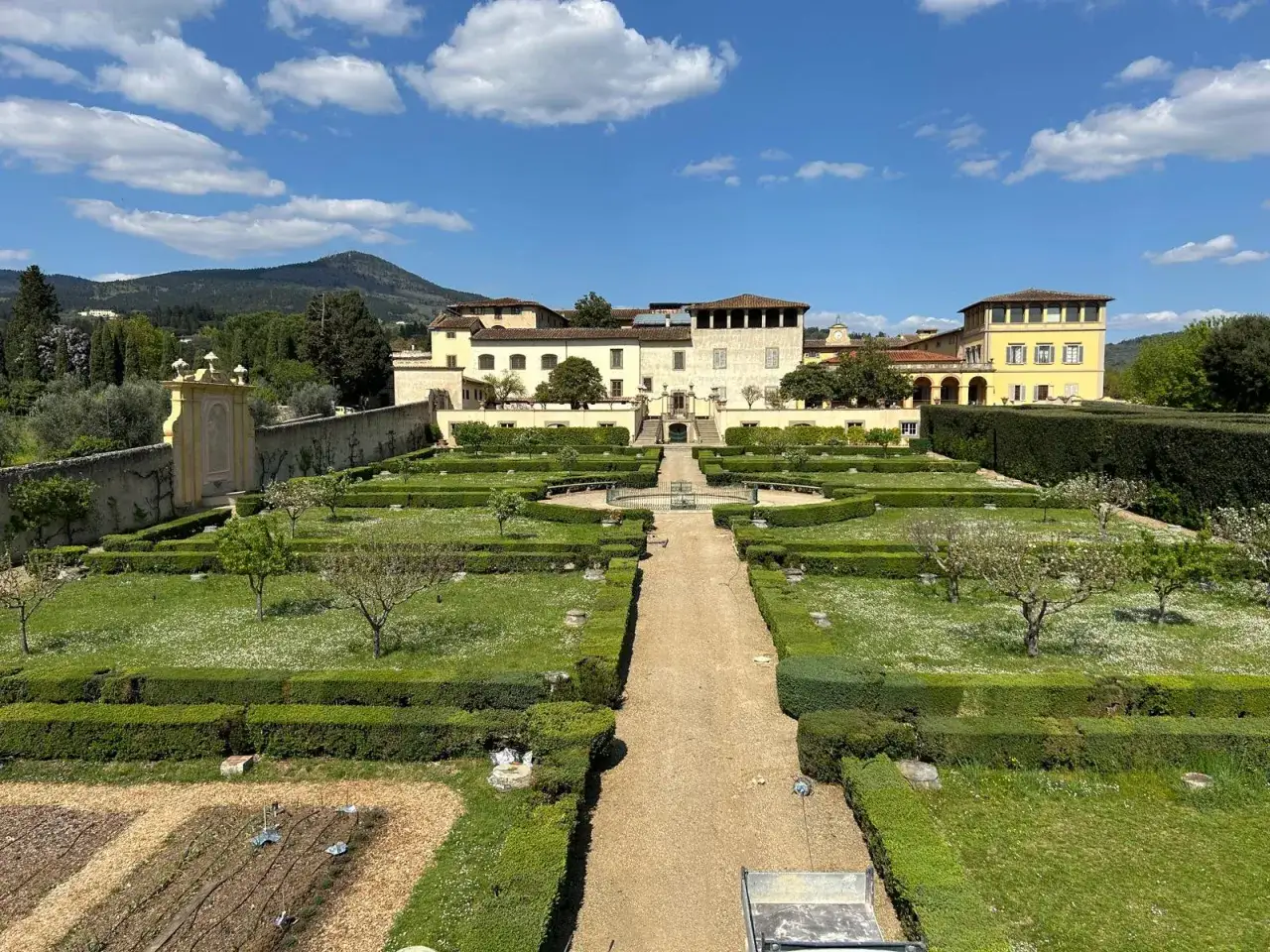 Giardini all'italiana con siepi geometriche e un palazzo sullo sfondo, un paesaggio che ricorda la bellezza di Castel Fiorentino.