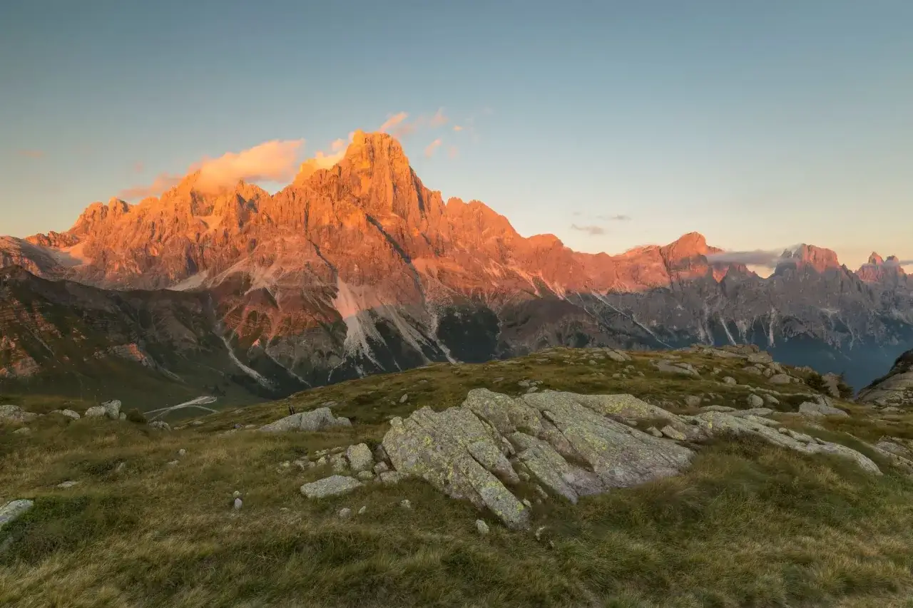 Le maestose Pale di San Martino illuminate dal sole al tramonto, con rocce muschiate in primo piano.