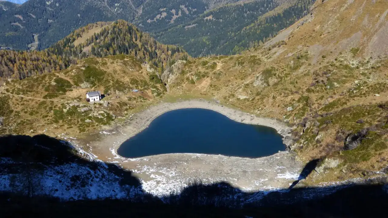 Un piccolo rifugio solitario veglia sul lago di Erdemolo, le cui acque blu intenso riflettono le montagne circostanti.