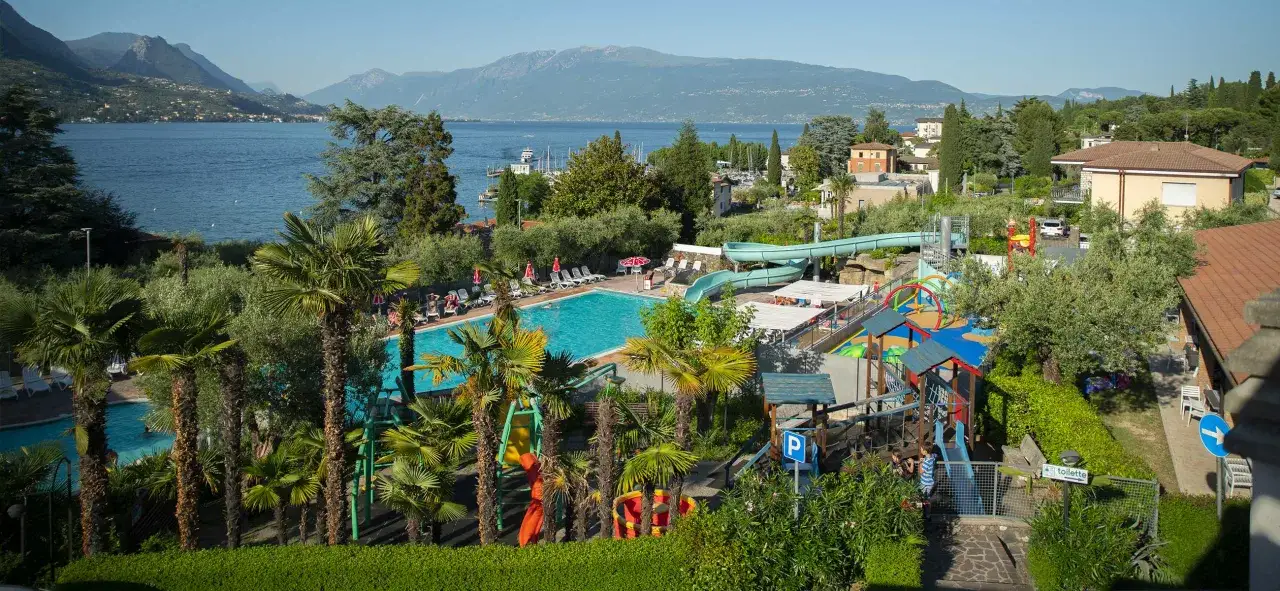 Vacanza al camping Maroadi: piscina, scivoli acquatici e parco giochi con vista lago e montagne.