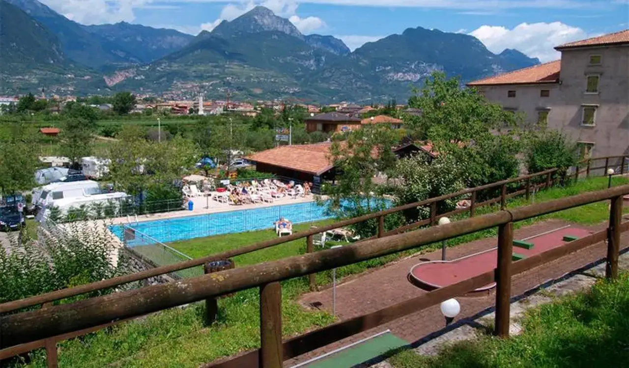 Un'area relax con piscina e campo da minigolf al camping Brione, circondata da montagne maestose.