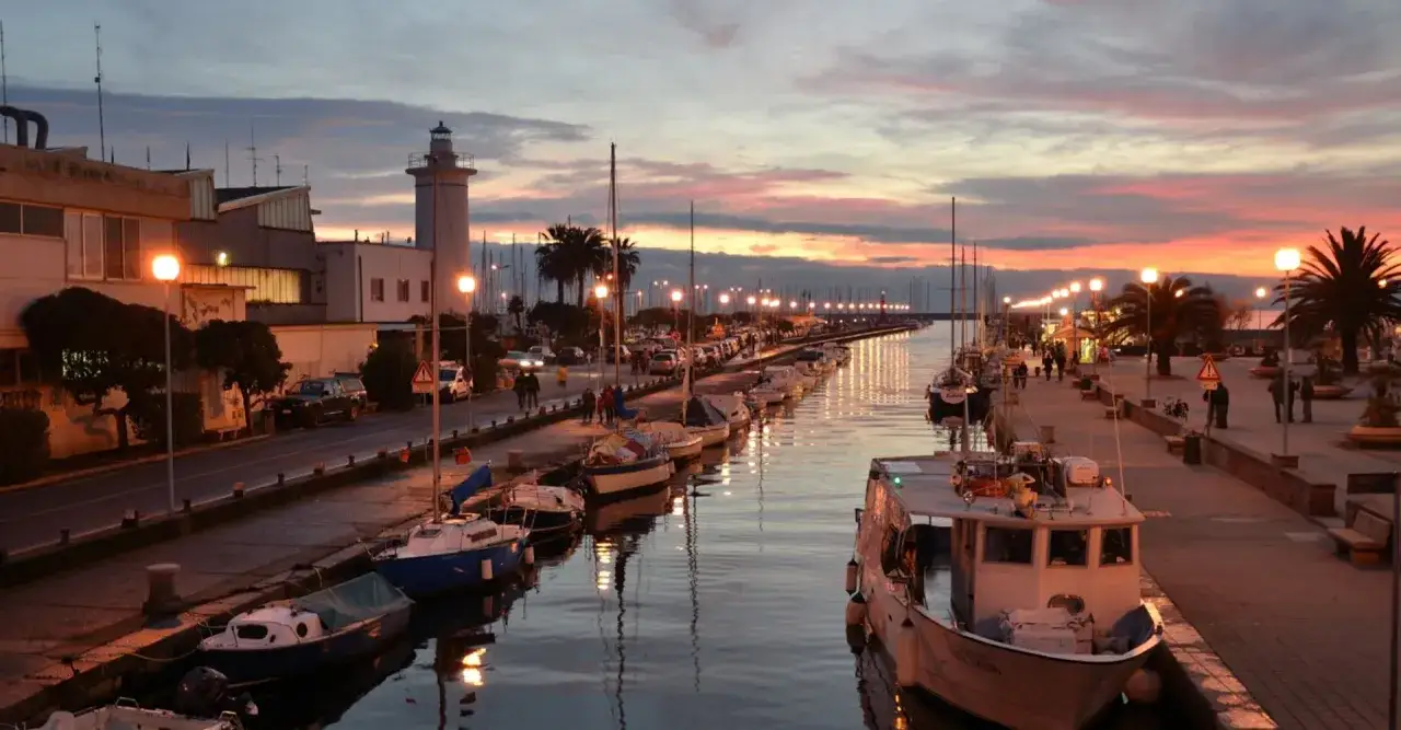 Tramonto sul porto di Viareggio, con barche ormeggiate e un faro. Perfetto per scoprire cosa fare a Viareggio.