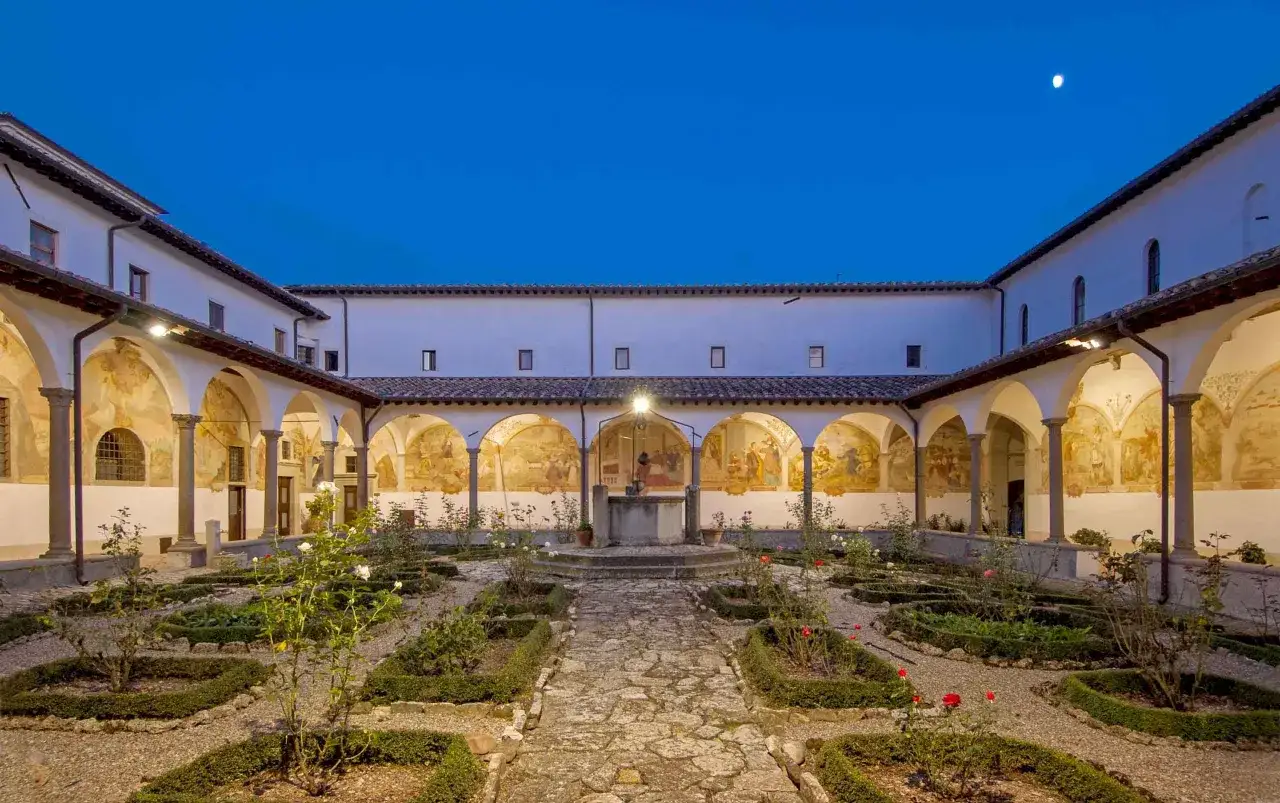 Cortile con affreschi e giardino fiorito. Un luogo incantevole per scoprire cosa vedere a Bibbiena, con un pozzo antico al centro.