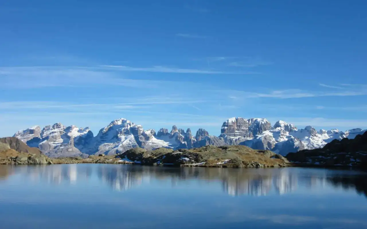 Lago alpino con montagne innevate sullo sfondo, un paesaggio mozzafiato vicino al rifugio Cornisello.