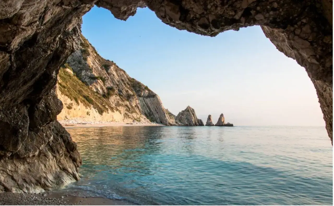 Vista da una grotta sul mare delle Marche, con scogliere a picco e faraglioni. Un luogo incantevole da scoprire.