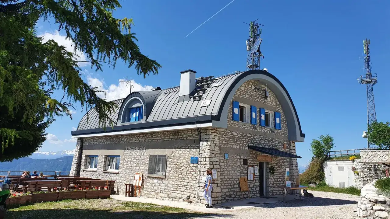 Rifugio sul monte Finonchio, con tetto spiovente, antenne e vista sulle montagne.