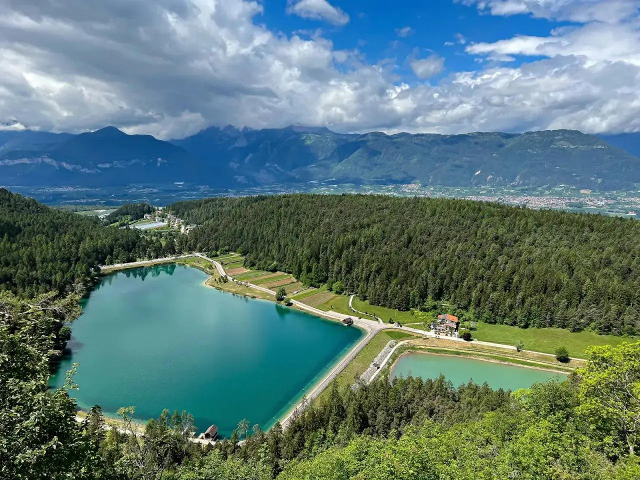 Vista panoramica del lago di Tavon, con le sue acque turchesi circondate da fitti boschi e montagne sullo sfondo.