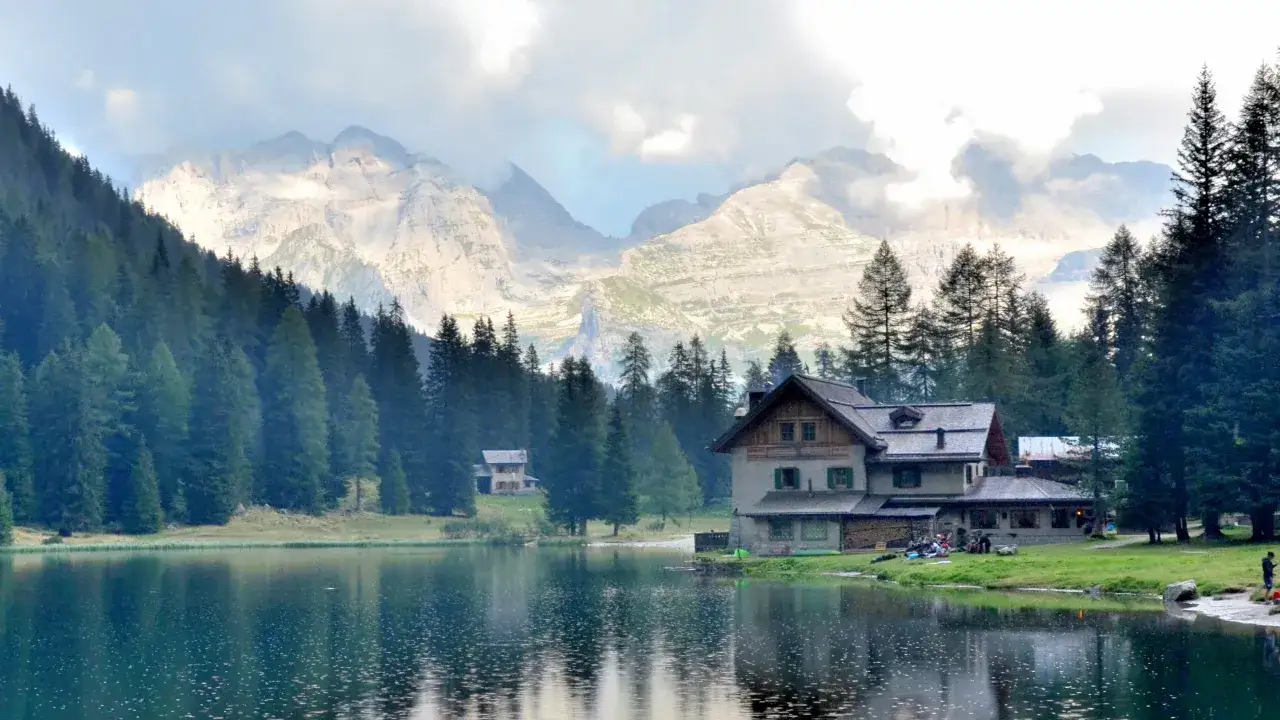 Riflessi sul lago Nambino, con un rifugio alpino e montagne imponenti sullo sfondo.