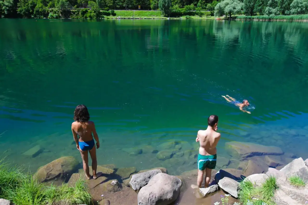 Coppia al lago di Lases, uno nuota, l'altra osserva le acque cristalline.