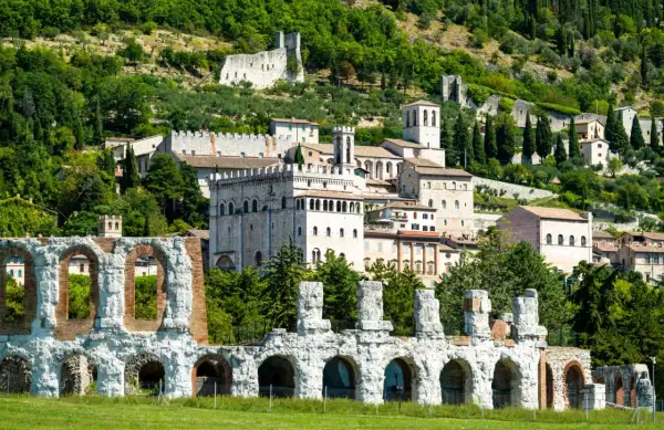 Rovine antiche e borgo medievale a Gubbio, Umbria, con vista sulle colline verdi. Un viaggio da Perugia a Gubbio tra storia e natura.