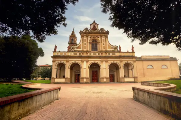 La facciata imponente di una chiesa a Castel Fiorentino, con un portico ad archi e un campanile.