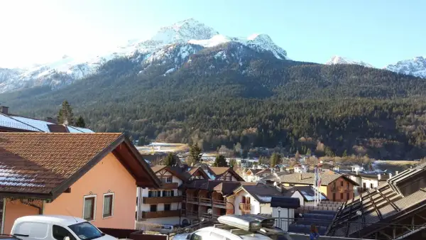 Paesaggio invernale con montagne innevate e un villaggio alpino. Si intravede un hotel ad Andalo.