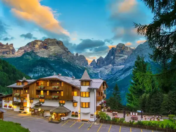Un incantevole hotel alpino a Madonna di Campiglio, con le maestose Dolomiti sullo sfondo al tramonto.