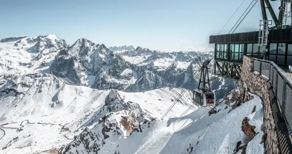 Panoramica mozzafiato dal belvedere di Canazei: una funivia scende tra le cime innevate delle Dolomiti.
