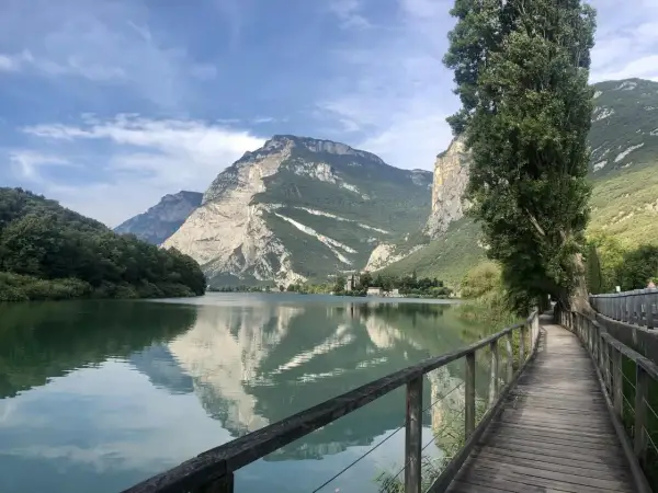 Passeggiata sul lungolago di Toblino, con montagne maestose che si specchiano nelle acque calme.