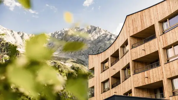 Il Falkensteiner Hotel Antholz si fonde con le maestose montagne. Architettura moderna in legno e natura incontaminata.